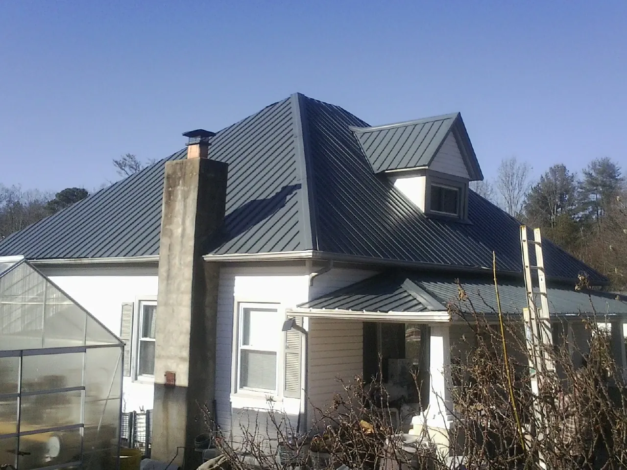 Dark blue standing seam metal roof on a white farmhouse with dormer — Slate & Tile Roof Repair by Roofing Brothers in Toppenish
