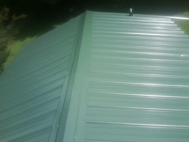 New green metal panels meeting at the ridge of a roof — Flat Roof Repair work by our crew in Toppenish