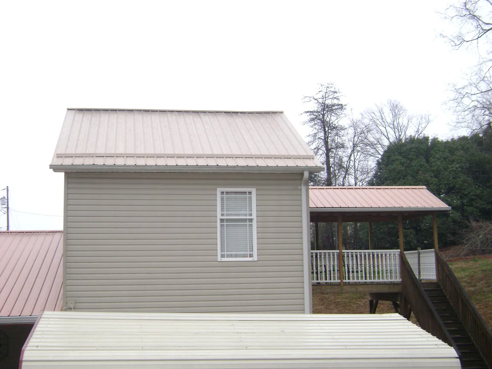 Tan metal roofs on a two story addition and attached porch, from a Roof Replacement job in Toppenish