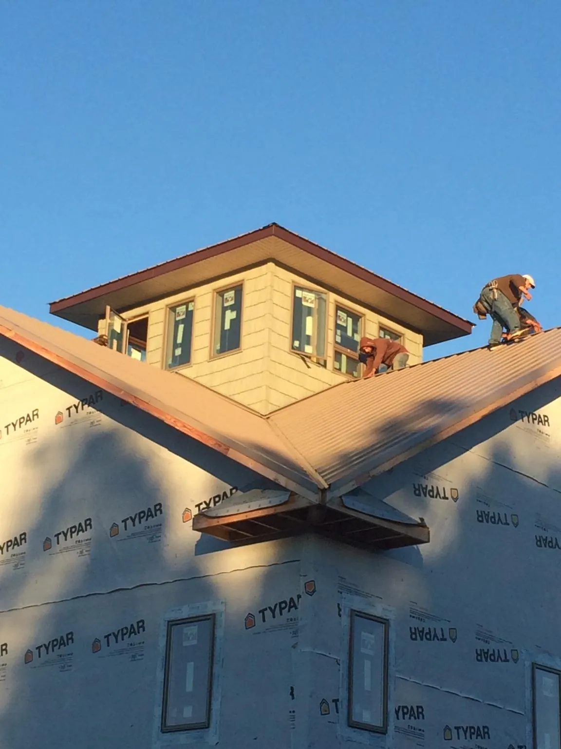 Roofers working around a rooftop cupola on a new metal roof at sunset — Roof Waterproofing in Toppenish by Roofing Brothers